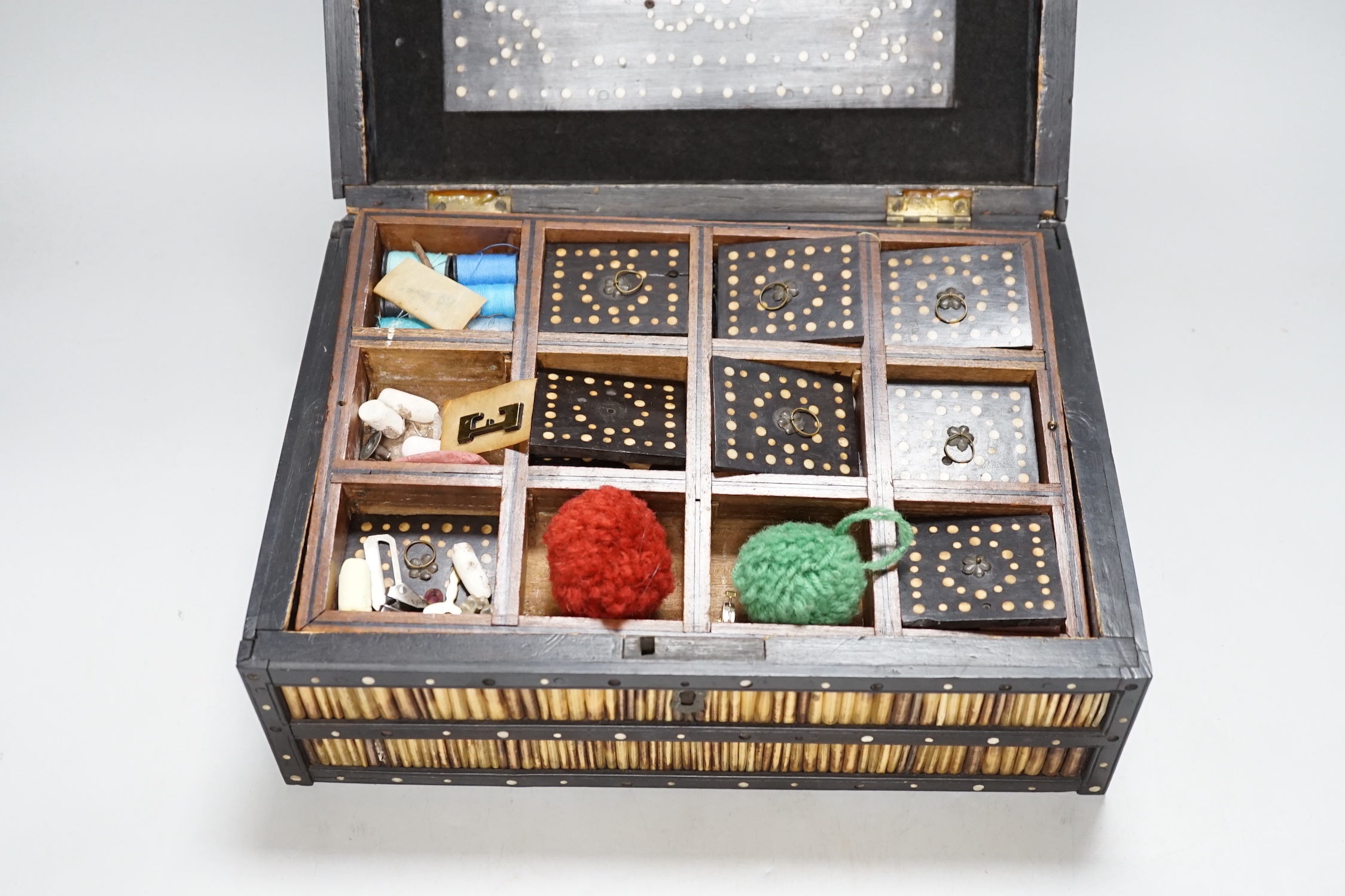 A 19th Century Ceylonese ebony, porcupine quill and bone inlaid sewing box with contents including cotton reels, 28cm wide